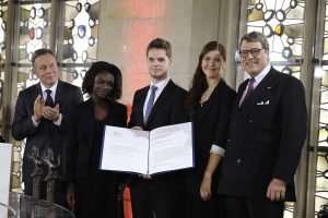 Die Vertreter der Aktion "Sühnezeichen Friedensdienste" Sally Eshun, David Szustkowski und Eva Kell (m.) nehmen stellvertretend die Auszeichnung von Dr. Reinhard Zinkann (re.) entgegen. (Foto: WWL)