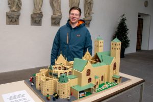 Janis Jaspers vor seinem Lego-Modell des St.-Paulus-Domes, das derzeit im Kreuzgang des Domes steht. (Foto: Bischöfliche Pressestelle / Ann-Christin Ladermann)