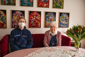 Bundesfreiwilliger Jan Keno Warnecke mit der 5000. Hausnotruf-Kundin Frieda Fischer, die sich über einen Blumenstrauß freute. (Foto: Malteser)