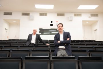 Allein im Hörsaal, der eigentlich bis auf den letzten Platz gefüllt wäre: das Moderatorenduo der „Ausgezeichnet.“ Prof. Dr. Richard Korff (l.) und Carsten Schröder. (Foto: FH Münster/Katharina Kipp)