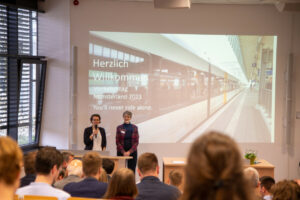 Prof. Dr. Jeanette Klemmer (l.) und Prof. Dr. Birgit Hartz begrüßten rund 120 Teilnehmende zum Verkehrstag Münsterland unter dem Motto: „You'll never ride alone - Was / wen bewegt der ÖPNV im Münsterland?“ (Foto: FH Münster / Michelle Liedtke)