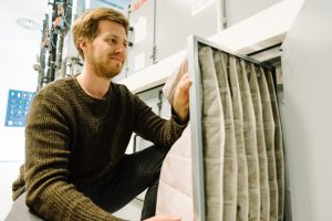 EPA-Filter sind besonders feine Taschenfilter, die selbst feine Aerosole filtern können. Der wissenschaftliche Mitarbeiter Steffen Jacobs baut hier einen neuen Filter in eine Klimaanlage ein. (Foto: FH Münster/Maxi Krähling)