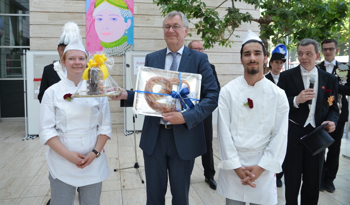 Regierungspräsident Prof. Dr. Reinhard Klenke (Mitte) freut sich über Baumkuchen und Brezel der Bäckergilde und Konditoren-Innung Münsterland. (Foto: RP)