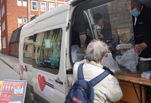 Helfer verteilen vor dem Borromaeum warme Mahlzeiten an Bedürftige. (Foto: Malteser Münster / Hölschermann)