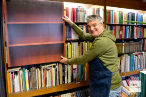 Die Tricks der Filmemacher: Michael Solder mit einem bedruckten Brett vor der Regalwand. Durch das Fenster sieht es so aus, als wäre das Regal leer. (Foto: Michael Bührke)