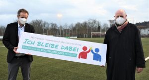 „Ich bleibe dabei“ und „Stay in your Club“ heißt es auf zwei Logos, mit denen die Mitglieder des Stadtsportbundes im Rahmen einer Kampagne zum Verbleib in und zur Solidarität mit ihren Sportvereinen aufgerufen werden. Gemeinsam mit SSB-Chef Michael Schmitz (li.) solidarisierte sich auch OB Lewe. (Foto: SSB)