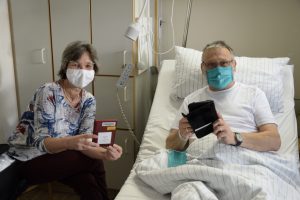 Susanne Amberg, Bibliothekarin in der Patientenbücherei des St. Franziskus-Hospitals, zeigt Günter Stryk das neue Angebot der „Onleihe“. (Foto: St. Franziskus-Hospital)