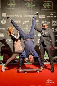 Gastgeber Titus Dittmann (re.) und die Moderatoren Lisa Feller und André Gatzke (kopfüber auf dem Skateboard) führten gut gelaunt durch den Abend. (Foto: Bastian E.)