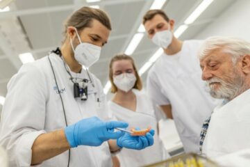 Studentin Jule König während einer Wurzelkanalbehandlung - Zahnärztin Dr. Laurentia Schuster (l.) und Assistenz Anh Gnoc Le begutachen ihre Arbeit (Foto: WWU / P. Leßmann)