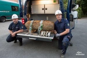 Peter Asmussen (li.) und Horst Schöwe vom Kampfmittelbeseitigungsdienst der Bezirksregierung mit der entschärften Bombe auf dem Gelände der Pötterhoek-Schule. (Foto: Thomas Hölscher)