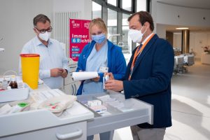 Prof. Alex W. Friedrich macht sich vor Ort selbst ein Bild von der mobilen Stationsapotheke im Gespräch mit der Medizinischen Fachangestellten Veronika Clees und Michael Klatthaar, Leiter des UKM Trainingszentrums. (Foto: UKM / Wibberg)