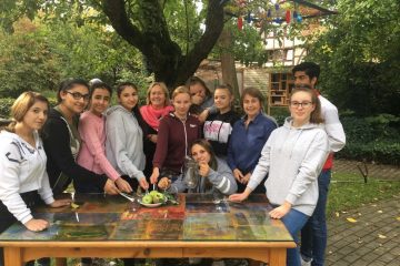 Sie sammelten Rezepte und entwarfen ein Kochbuch – Schülerinnen und ein Schüler der Waldschule Kinderhaus am „Tisch der Verständigung“ mit Lehrerin Gisela Klatt (Mitte) und Karin Gindler-Hilge (re.). (Foto: Gintare Skroblyte)