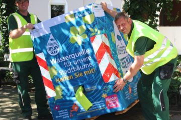 Foto: Fabian Böckmann (l.) und Bernd Lohmann vom Amt für Grünflächen, Umwelt und Nachhaltigkeit stellen im Hansaviertel an der Meppener Straße/Ecke Papenburger Straße einen der 37 Wassercontainer auf. (Foto: Stadt Münster)