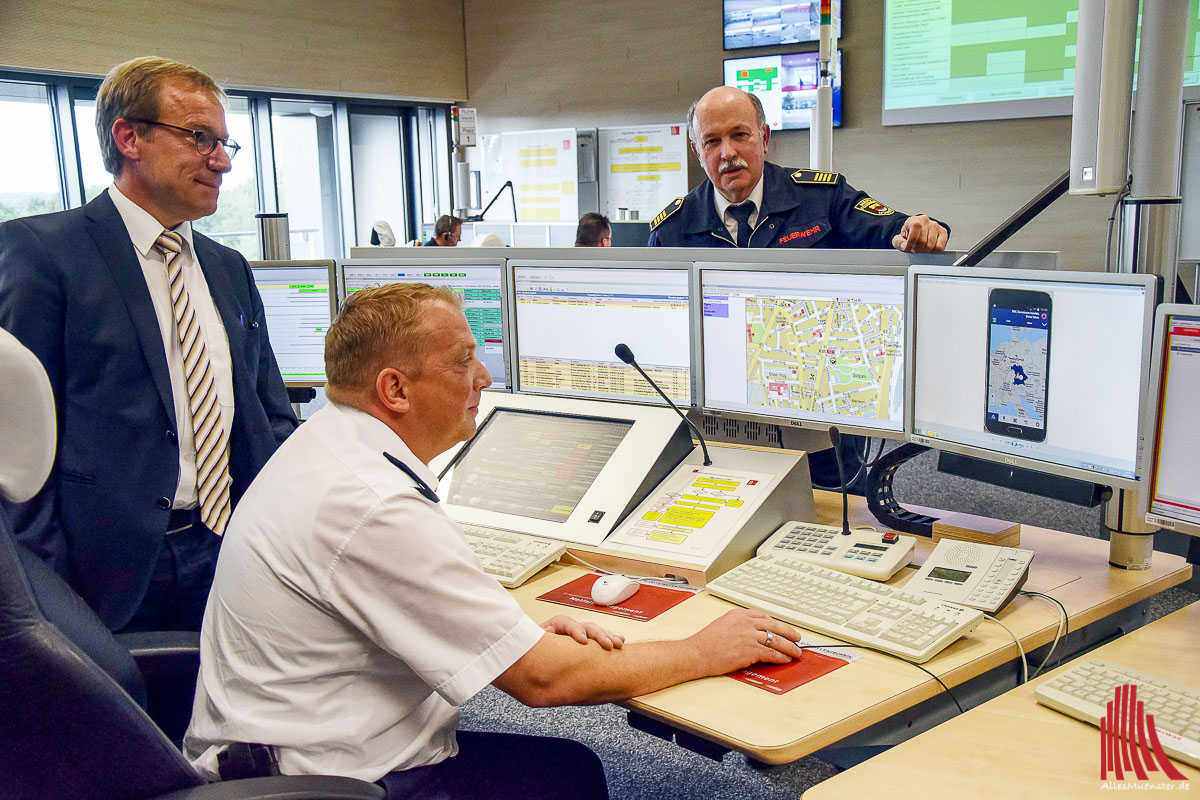 (v.l.) Wolfgang Heuer, Stadtrat und Leiter des Krisenstabes, Rolf Kenter, Fachstellenleiter der Leitstelle und des Katastrophenschutzes und Benno Fritzen, Leiter der Feuerwehr Münster, erklärten die Anwendung der Smartphone-App NINA in der Einsatzleitstelle.