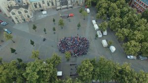 Flashmob auf dem Domplatz. Die kleine Gruppe links stellt die Menge der nach Deutschland Geflüchteten im letzten Jahr dar, die große Menge rechts die deutsche Bevölkerung. (Foto: Drones Photography / David Schnitker)